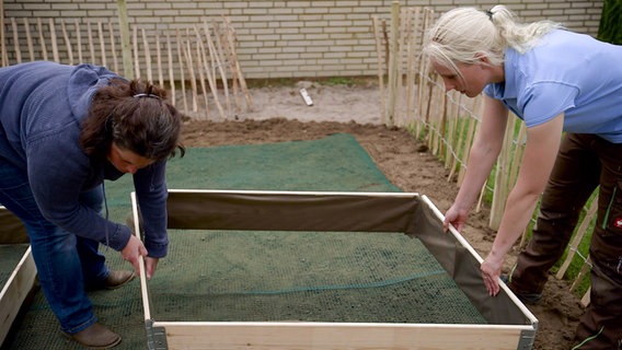 Garten-Doc Lisa Willers setzt einen  Hochbeet-Rahmen auf die vorbereitete Fläche. © NDR/nonfictionplanet 