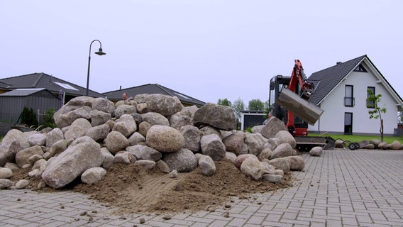 Rund 25 Tonnen Feldsteine liegen auf dem Platz vor einem Garten © NDR/nonfiction planet 