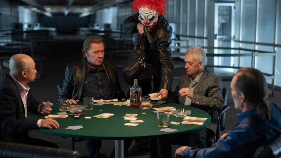 Undercover-Ermittlungen gegen das illegale Glücksspiel: Dirk Matthies' (Jan Fedder, 2.v.l.) Pokerrunde (Komparsen) wird Minuten vor der Razzia von einem als Clown maskierten Räuber überfallen und ausgeraubt. © NDR/ARD/Thorsten Jander 