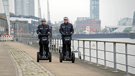 Paul Dänning (Jens Münchow, l.) und Piet Wellbrook (Peter Fieseler, r.) müssen auf Anweisung von Frau Küppers mit Segways Streife fahren. Paul Dänning (Jens Münchow, l.) und Piet Wellbrook (Peter Fieseler, r.) müssen auf Anweisung von Frau Küppers mit Segways Streife fahren. © NDR/ARD/Thorsten Jander