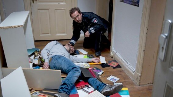 Paul Dänning (Jens Münchow, r.) findet den Studenten Faza (Komparse) zusammengeschlagen in seiner verwüsteten Wohnung. © NDR/ARD/Thorsten Jander 