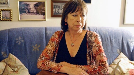 Eine Frau sitzt mit einer Kiste auf dem Schoß auf einem Sofa. Ihr Blick ist betrübt. © NDR/ARD/Markus Hertrich Foto: Markus Hertrich