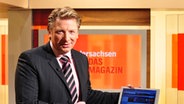 Moderator Ludger Abeln deutet im Niedersachsen 19.30 Studio auf ein Laptop mit der Sendungs-Website. © NDR Foto: Sven Glagow