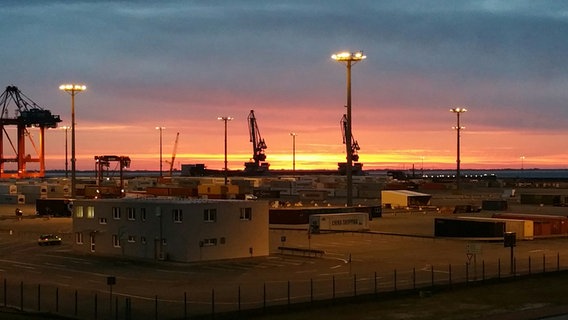 Der Himmel über dem JadeWeserPort ist von der Sonne rötlich gefärbt. © NDR Foto: Klaus Böhme