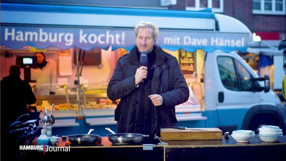 Moderator und Koch Dave Hänsel steht vor einem Stand auf einem Hamburger Wochenmarkt. © Screenshot 