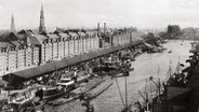 Sandtorhafen, etwa 1889: Seeschiffe liegen umringt von kleineren Schuten an der Kaimauer, dahinter die gerade errichtete Speicherstadt. © Hamburger Hafen und Logistik AG 