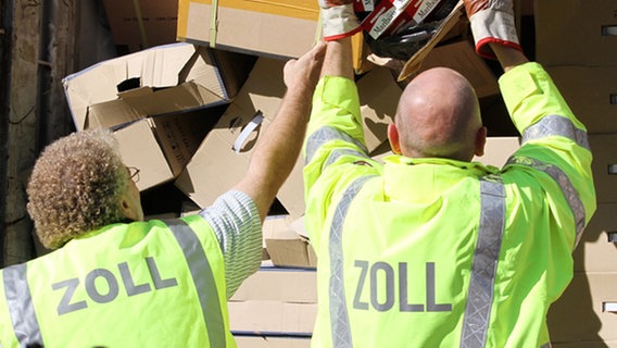 Beamte des Hamburger Zollfahndungsamts entladen einen Container mit geschmuggelten Zigaretten.  Foto: Bodo Marks