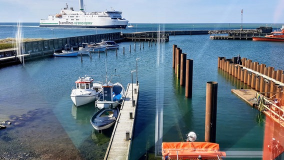 Anleger der Seenotretter im Hafen von Gedser. Eine Fähre fährt links hinten über das Wasser. Kleine Boote am Anleger sind im Vordergrund zu sehen.  Foto: Martin Möller