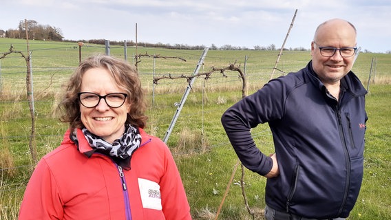Eine Frau steht links und ein Mann rechts im Bild. Sie sind Weinbauern und stehen vor Weinreben.  Foto: Martin Möller