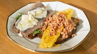 Matjes und Krabben-Omelett auf Schwarzbrot auf einem Teller serviert. © NDR/Doclights GmbH 