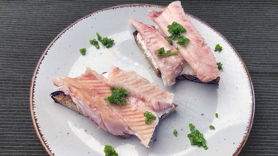Mit Räucherfisch belegte Brote auf einem Teller serviert. © NDR/megaherz GmbH 