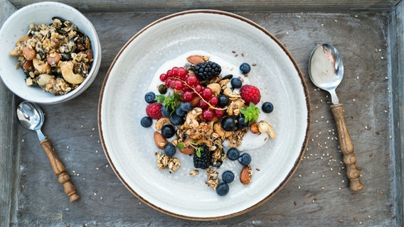 Granola mit Kokosjoghurt und frischen Beeren auf einem Teller angerichtet. © NDR Foto: Tarik Rose