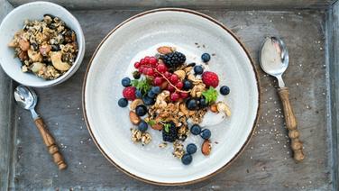 Granola with coconut yogurt and fresh berries served on a plate.  © NDR Photo: Tarik Rose