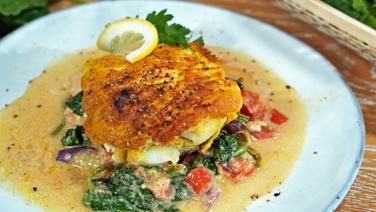 Cod fillet in eggshell served with spinach and sauce on a plate.  © NDR Photo: Florian Kruck