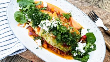 Vegetarische Kohlroulade mit Gemüse und Kräutern auf einem Teller angerichtet. © NDR Foto: Tarik Rose