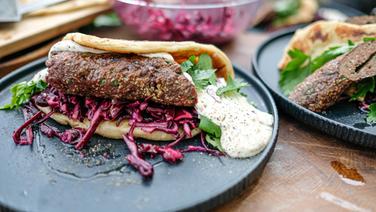 Venison kebab served with naan bread and red cabbage salad on a plate.  © NDR Photo: Tarik Rose