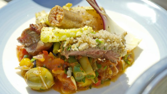 Rindfleisch mit Kräuter-Senf-Kruste auf Tomaten-Merguez-Sugo an
Blumenkohl-Chips und roten Kartoffeln auf einem Teller angerichtet © NDR Foto: Tarik Rose