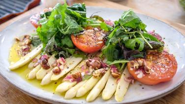 Gegrillter Spargel mit Tomaten, Salat und Haselnuss-Vinaigrette auf einem Teller serviert. © NDR Foto: Tarik Rose