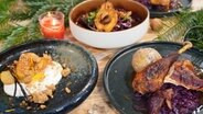 Bauernhuhn mit Knödeln und Rotkohl, Rotkohlsalat mit Birne und Vanillequark mit Äpfeln auf Tellern angerichtet. © NDR Foto: Tarik Rose