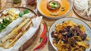 Ein Teller Currysuppe, Schwarzwurzeln in Pergament und Ragout vom Rind mit Pappardelle auf einem Tisch angerichtet. © NDR Foto: Florian Kruck