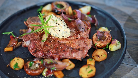 Schweinekotelett mit Pastinaken und Kräuterbutter auf einem Teller angerichtet © NDR Foto: Tarik Rose