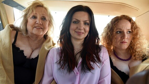 Szenenbild aus der Comedy-Serie "Jennifer - Sehnsucht nach was Besseres": Oma Margret (Doris Kunstmann, l.), Jenni (Katrin Ingendoh, Mi.) und Melli (Laura Lo Zito, r.) sitzen im Auto auf dem Rücksitz. © NDR/Marion von der Mehden 