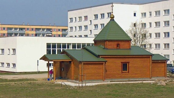 Eine russisch-orthodoxe Kirche aus Holz mitten in Plattenbauten.  