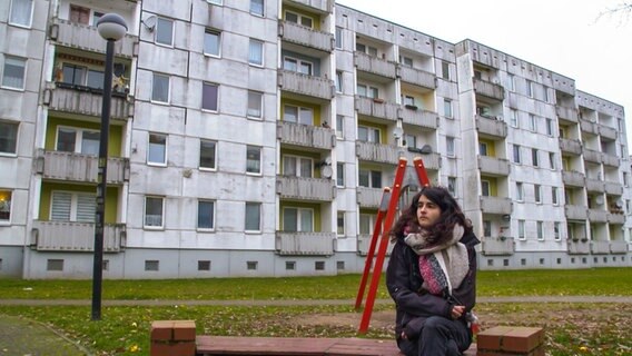 Ein junger Mann sitzt vor einem Plattenbau © NDR Fernsehen/Kulturjournal 