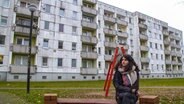 Ein junger Mann sitzt vor einem Plattenbau © NDR Fernsehen/Kulturjournal 