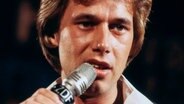 Ein Mann hält ein Mikrofon an seinen Mund © imago 