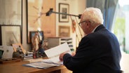 Ein Mann mit weißen Haaren und Anzug sitzt am Schreibtisch © NDR.de 