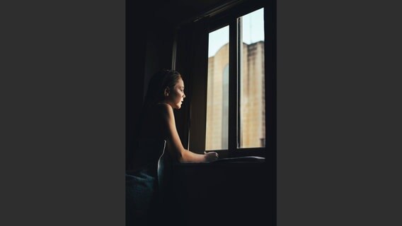 Ein Mädchen blickt aus einem Fenster © imago stock people/Aitor Carrera PortÃ© 