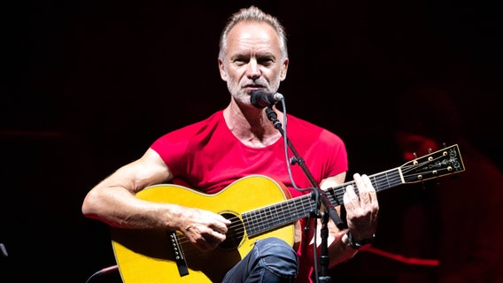 Sänger Sting sitzt auf einem Stuhl und spielt Gitarre © imago images / Pacific Press Agency 