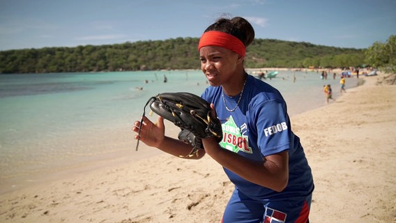 Chantel steht mit Baseball-Handschuh am Strand. © NDR/docstation/Marco Berger 