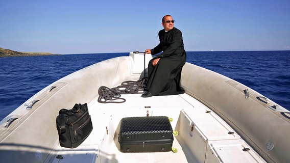 Ein Priester steuert ein Schlauchboot über das Meer. © NDR/nonfictionplanet/Florian Melzer, honorarfrei Foto: Florian Melzer