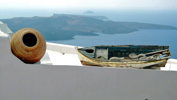 Ein Boot und Tonkrug auf einem Dach oberhalb des Meeres. © NDR 