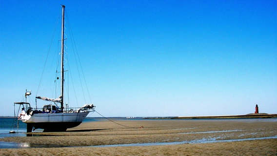 Ein kleines trockengefallenes Segelschiff liegt im Wattenmeer vor Langeneß im Nordfriesischen Wattenmeer. Ein kleines trockengefallenes Segelschiff liegt im Wattenmeer vor Langeneß im Nordfriesischen Wattenmeer. © NDR Foto: Thomas Schlick