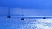 Segelboote in der blauen Stunde auf glitzerndem Wasser vor Sardinien. © NDR Foto: Wilfried Nagel