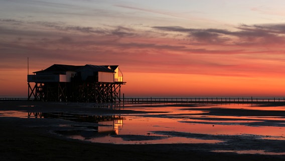 Pfahlbauten in St Peter Ording im roten Licht des Sonnenuntergangs. © NDR Foto: Regina Dohrn-Tiedemann