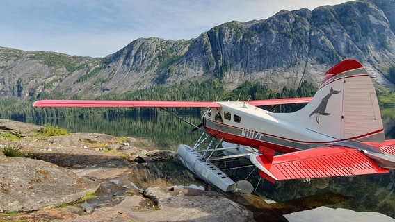 Ein rotes Wasserflugzeug steht an einem Fjord. © NDR/nonfictionplanet/Ralf Biehler 