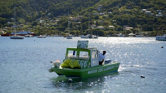 Ein kleines grünes Boot fährt an der Küste der Insel Bequia entlang. © NDR/nonfictionplanet/Florian Melzer 