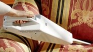 Eine Frauenhand mit Handstaubsauger über einem Sessel. © fotolia Foto: Miguel Garcia Saaved