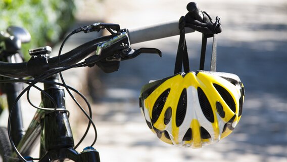 Fahrradhelm hängt an einem Fahrradlenker. © fotolia Foto: carballo
