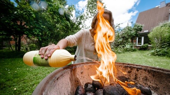 Eine Frau Gießt Spiritus auf Grillkohle in einem Grill. © picture alliance / dpa Themendienst Foto: Markus Scholz