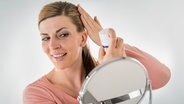 Eine Frau sprüht sich Haarspray auf die Frisur. © Picture-Alliance / dpa Themendienst Foto: Christin Klose