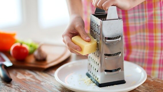 Käse wird mit Einsatz einer Käsereibe gerieben. © colourbox Foto: Syda Productions