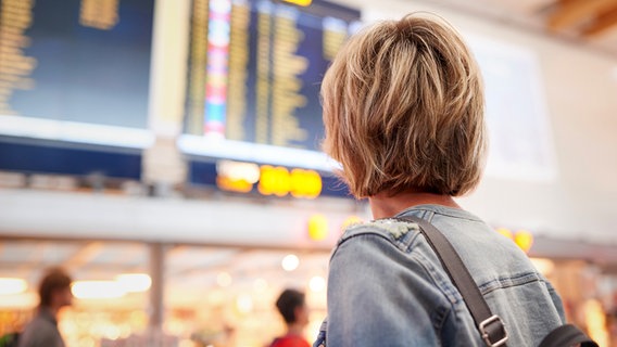 Frau schaut auf Display der Abflugzeiten am Airport © colourbox Foto: -