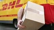 Ein DHL-Mitarbeiter trägt ein Paket. © picture alliance / dpa Foto: Oliver Berg