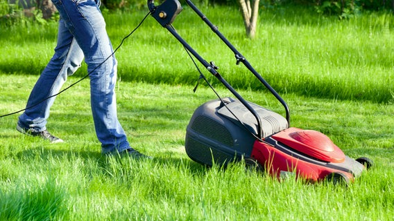 Person operating a lawn mower in a meadow © Fotolia.com Photo: maxoidos