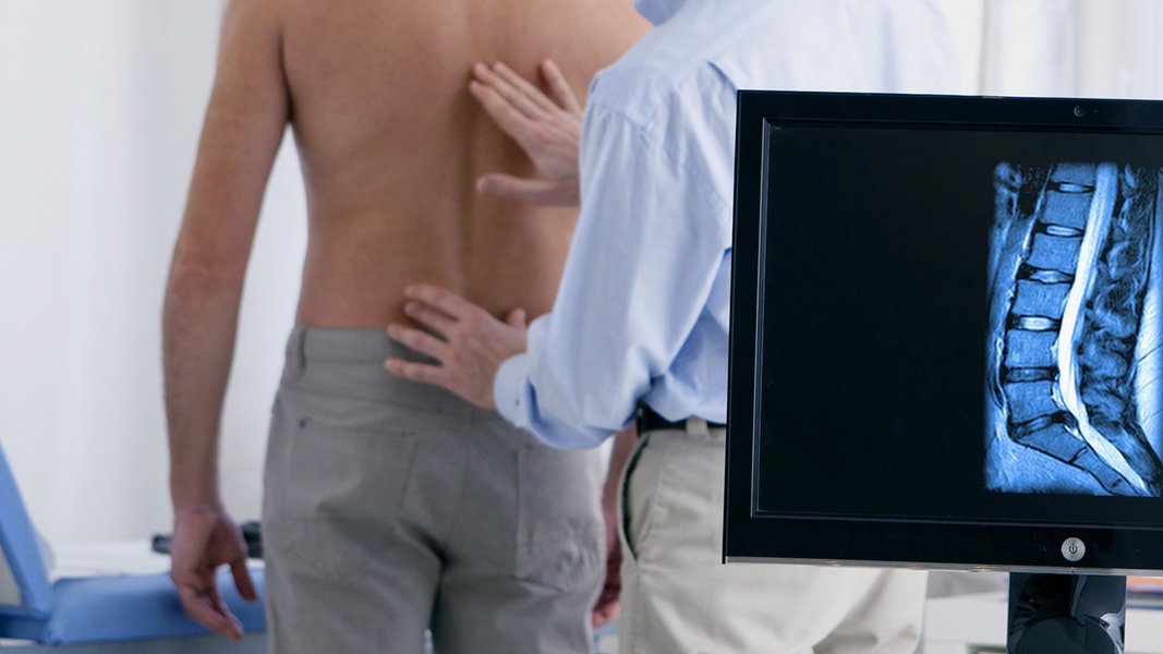 Arzt untersucht den Rücken eines Mannes. 